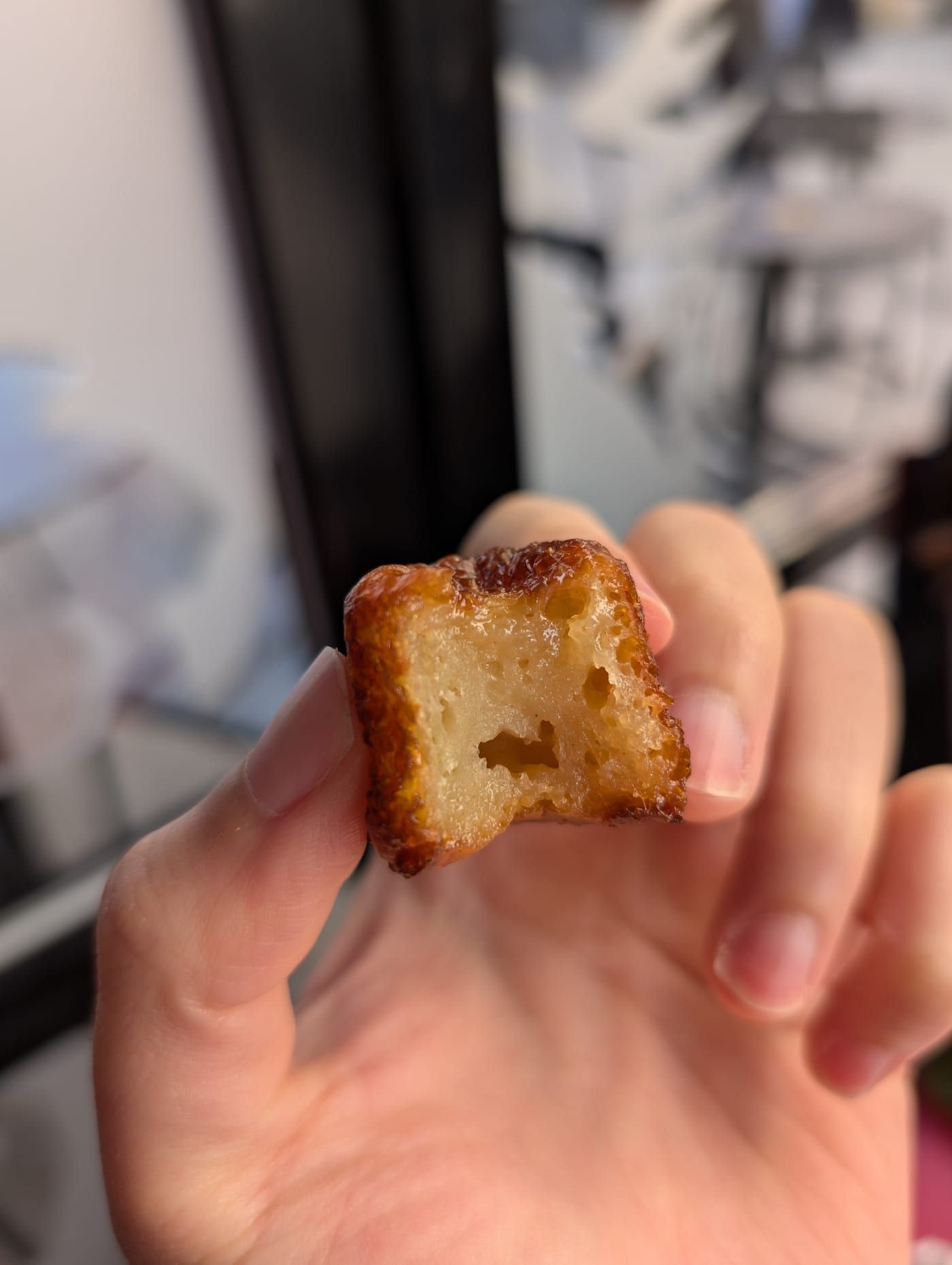 Un canelé bordelais à la croûte brun foncé, posé sur une assiette.