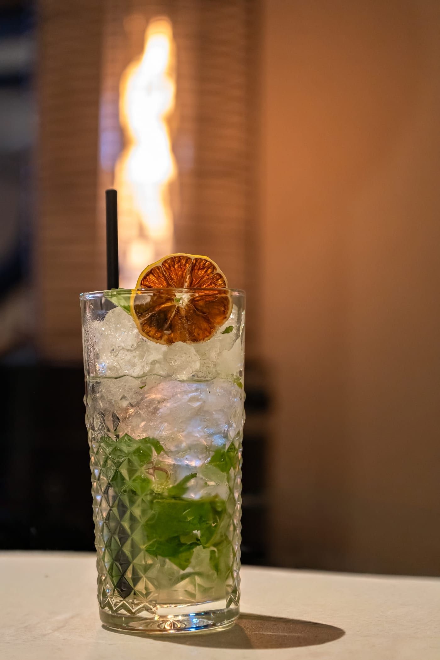Un mojito dans un verre highball, garni de feuilles de menthe fraîche et de citron vert, sur glace pilée.