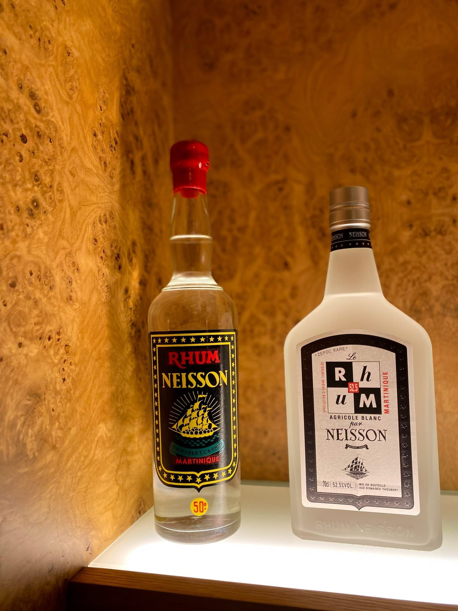 Deux bouteilles Neisson côte à côte : à gauche le Rhum Neisson 50° à l'étiquette au trois-mâts, à droite Le Rhum 52,5° dans sa bouteille carrée en verre dépoli.